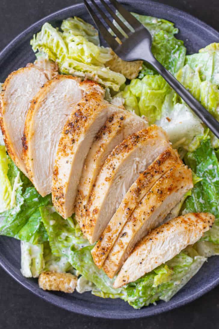 Chicken breast on a plate with Caesar salad.