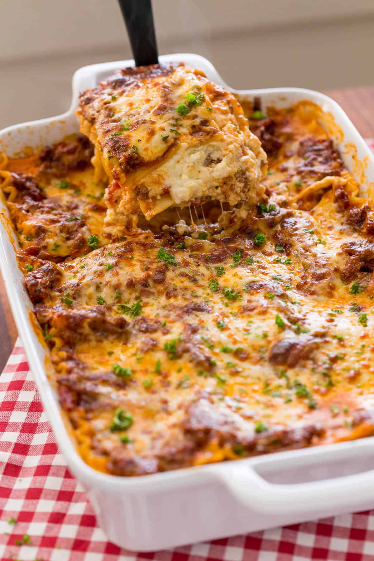 Piece of lasagna being lifted from baking dish